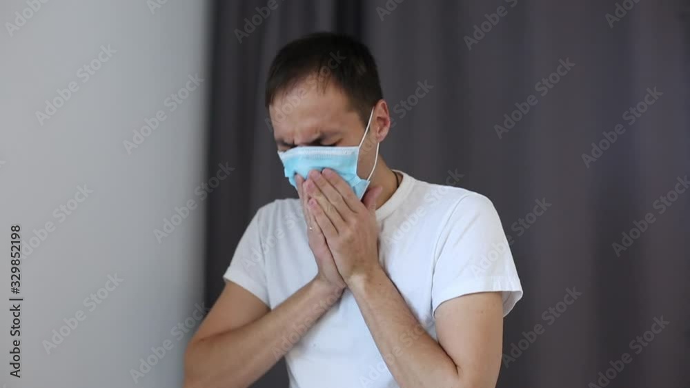 Portrait of the young Caucasian happy man physician taking off mask from his mouth and smiling cheerfully. Close up.
