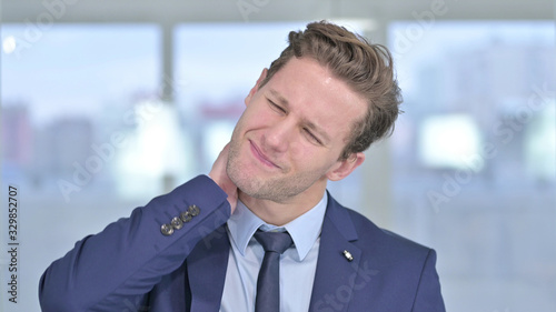 Portrait of Stressed Young Businessman having Neck Pain