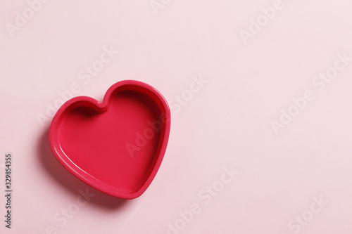 Colorful silicone cooking utensils in the shape of a heart on a pink background