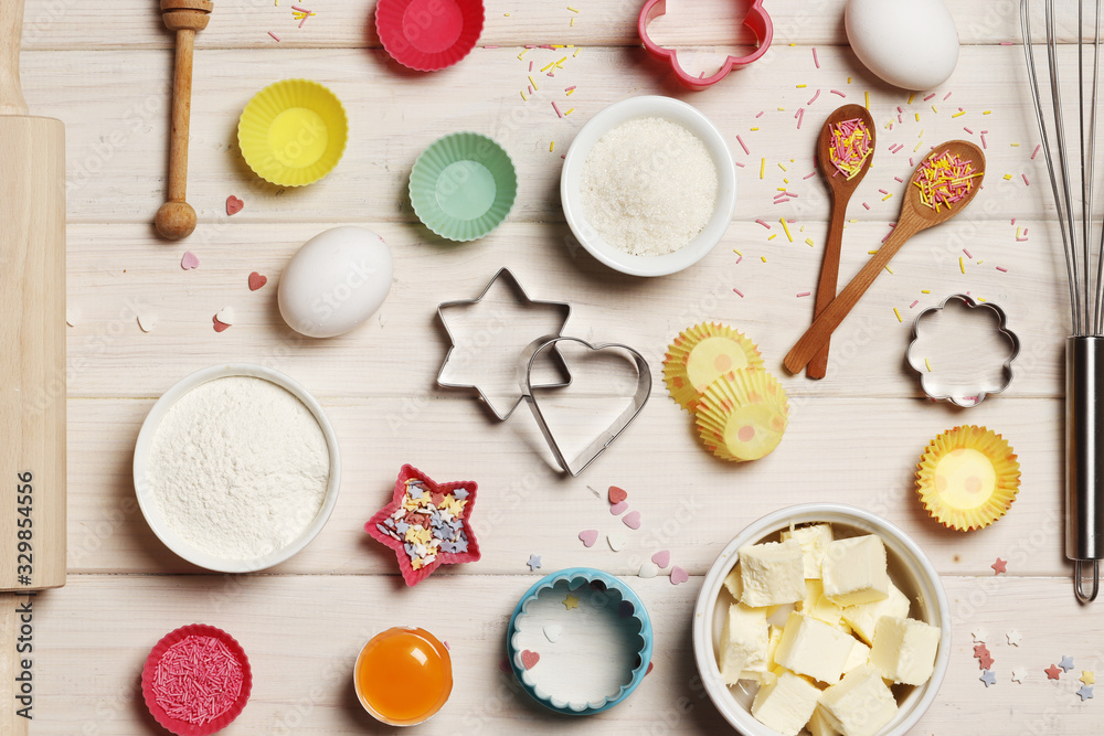 Baking utensils and ingredients. Colorful silicone cooking utensils, rolling pin, cookie mold,. cupcake cases and sugar sprinkling on a white wooden background. Easter concept. Baking utensils and ingredients. Colorful silicone cooking utensils, rolling pin, cookie mold,. cupcake cases and sugar sprinkling on a white wooden background. Easter concept.