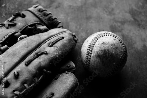 Grunge baseball background with old used ball and glove close up in black and white.