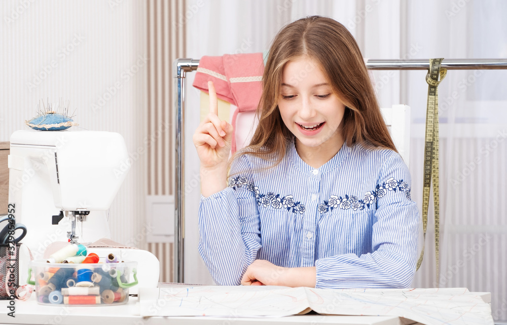Young tailor girl making new templates with pencil on cloth Young tailor girl making new templates with pencil on cloth