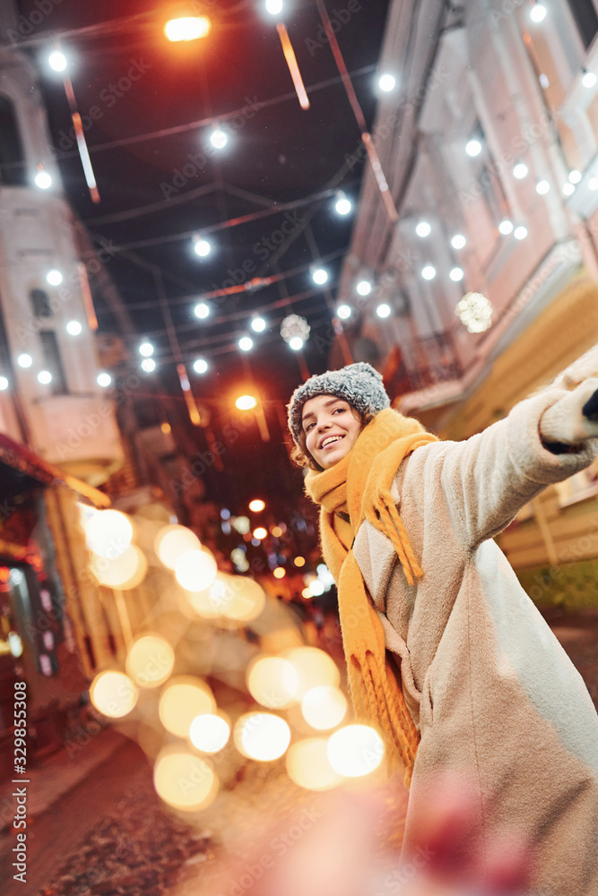 Happy young couple in warm clothes is on christmas decorated street together Happy young couple in warm clothes is on christmas decorated street together