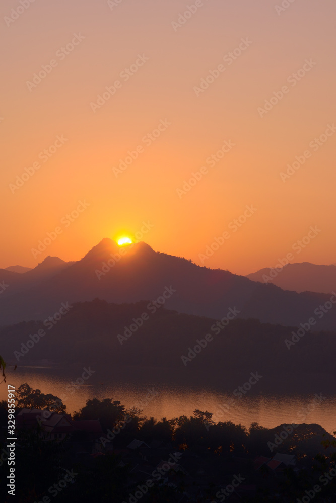 Glorious sunset over hazy mountains by the Mekong river. View from Mount Phou Si, in Luang Prabang, Laos.