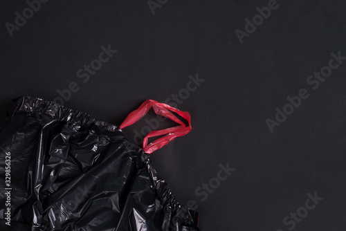 Plastic new empty disposable garbage bags on a black background. Top view.