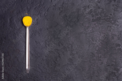 Turmeric on a wooden spoon on a black concrete background