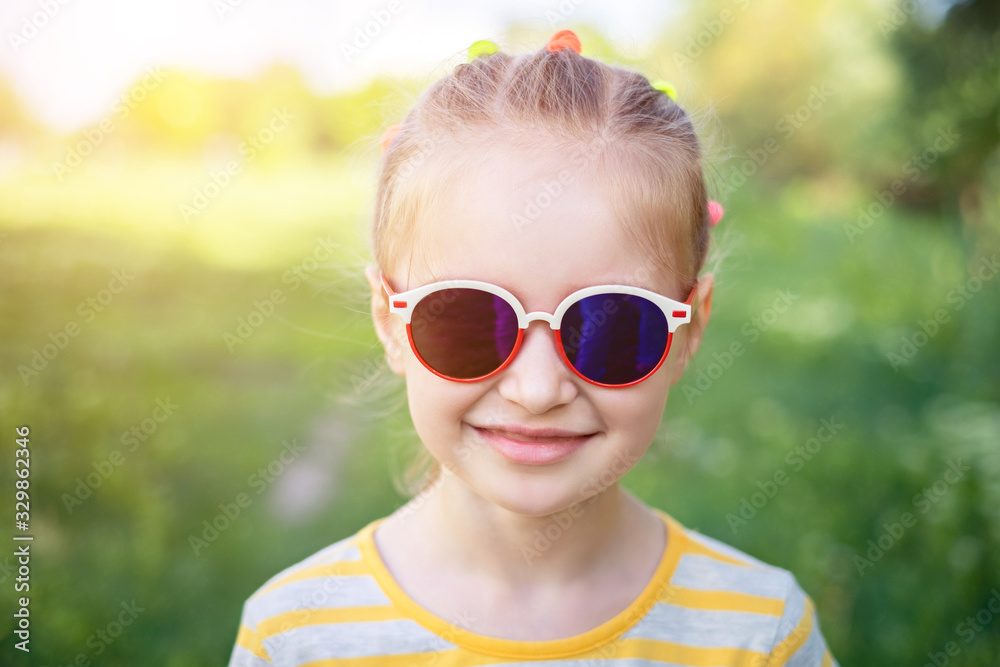 Portait of smiling girl child in modern pretty sunglasses on background of green park Portait of smiling girl child in modern pretty sunglasses on background of green park