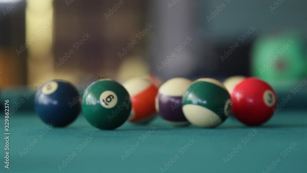 Close up at eye level of the cue ball hitting the apex ball on a green billiard table