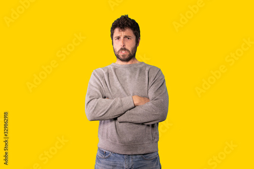 young handsome man feeling depressed and disappointed, looking serious, annoyed against yellow background
