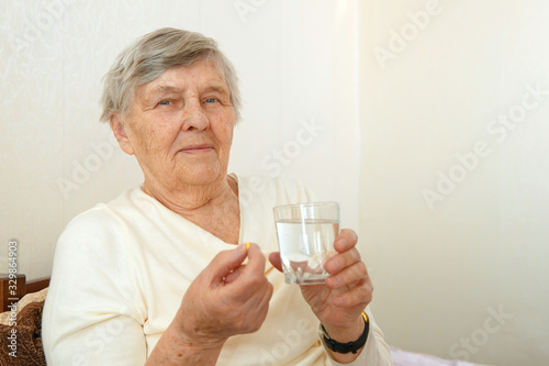 An elderly woman is going to swallow a medicine