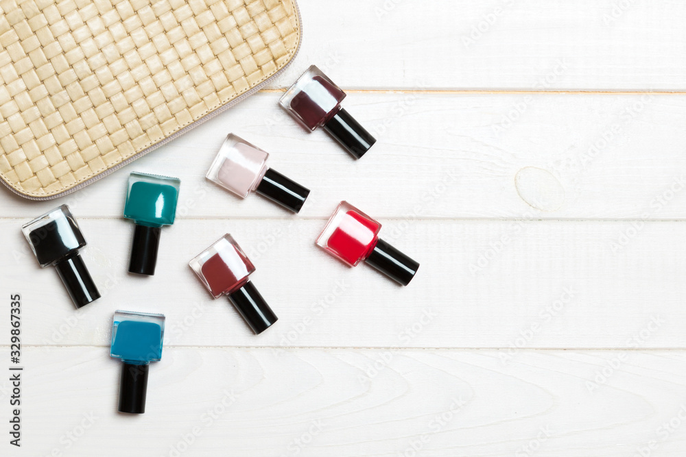Top view of the set of nail polishes and bright gel varnishes fallen out of cosmetics bag with copy space on wooden background. Trendy nail concept Top view of the set of nail polishes and bright gel varnishes fallen out of cosmetics bag with copy space on wooden background. Trendy nail concept