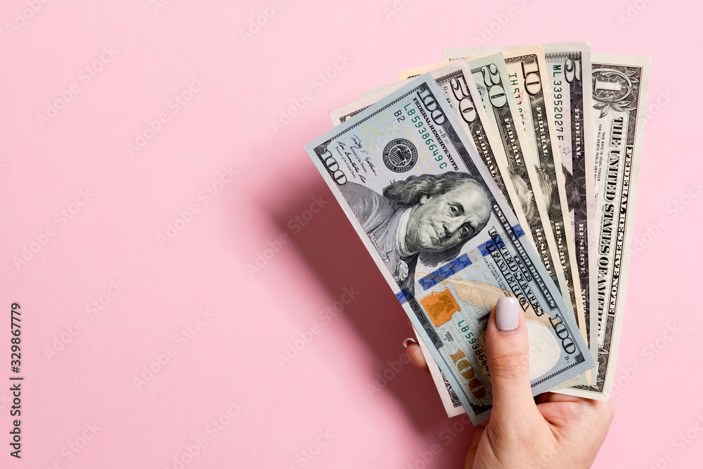 Top view of female hand holding a fan of money on colorful background. Various dollar bills. Credit and debt concept with copy space Top view of female hand holding a fan of money on colorful background. Various dollar bills. Credit and debt concept with copy space