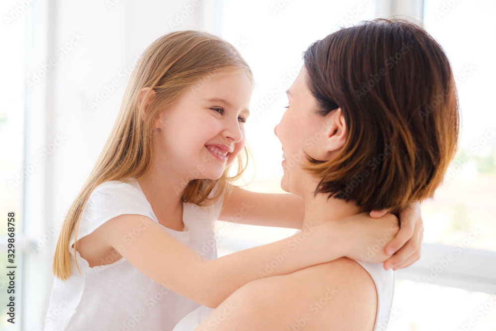 Mother with her little daughter girl hugging in white room Mother with her little daughter girl hugging in white room