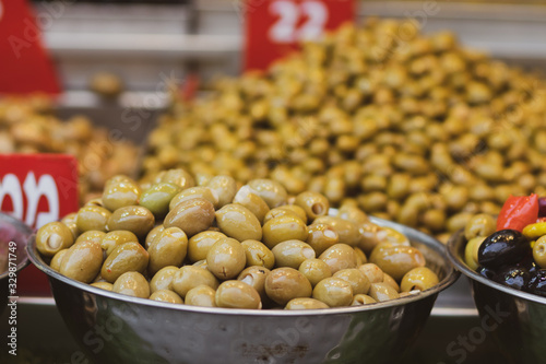 A pile of shiny Syrian green olives, full of oil. Inside a metal bowl. Arabic style. The Old Market of Mahane Yehuda, Jerusalem.