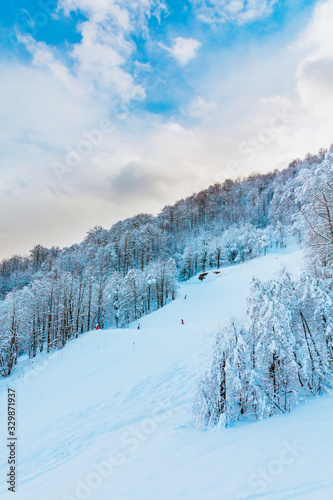 Ski resort panorama, chair lift going upstairs with unrecognizable riders on it,  view on great snowy mountains in sunny day, blue sky backwards. Horizontal picture with back light. Actual lifestyle. © localcinema