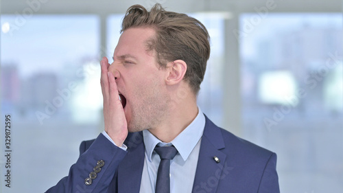 Portrait of Sleepy Young Businessman Yawning in Office © stockbakers