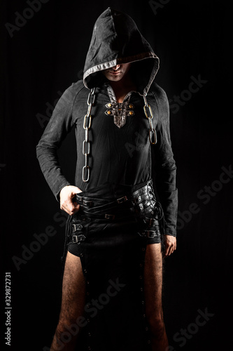 Young man posing in hooded gothic clothes with chain around neck