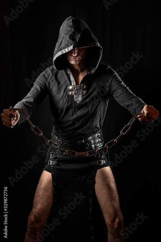 Young man posing in hooded gothic clothes looking grim photo