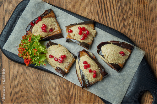 Traditional Georgian appetizer - fried eggplant with grated nut and pomegranate seeds on a wooden board. Top view, flat lay, copy space photo