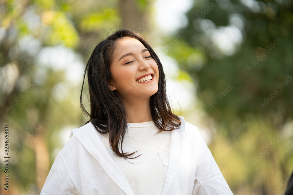 Portrait shot of happy, successful, attractive bearded of Asian woman with big smiling with a confident look toward the camera at a blur park background with copy space in natural sunlight. Portrait shot of happy, successful, attractive bearded of Asian woman with big smiling with a confident look toward the camera at a blur park background with copy space in natural sunlight.