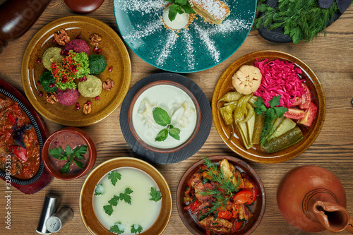 Georgian cuisine foodset from phali, lobio, ojahuri, pickled vegetables, chikhirtma and cake top view food on wooden table photo