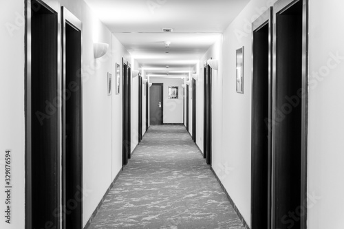 Fototapeta White corridor with black doors in the hotel