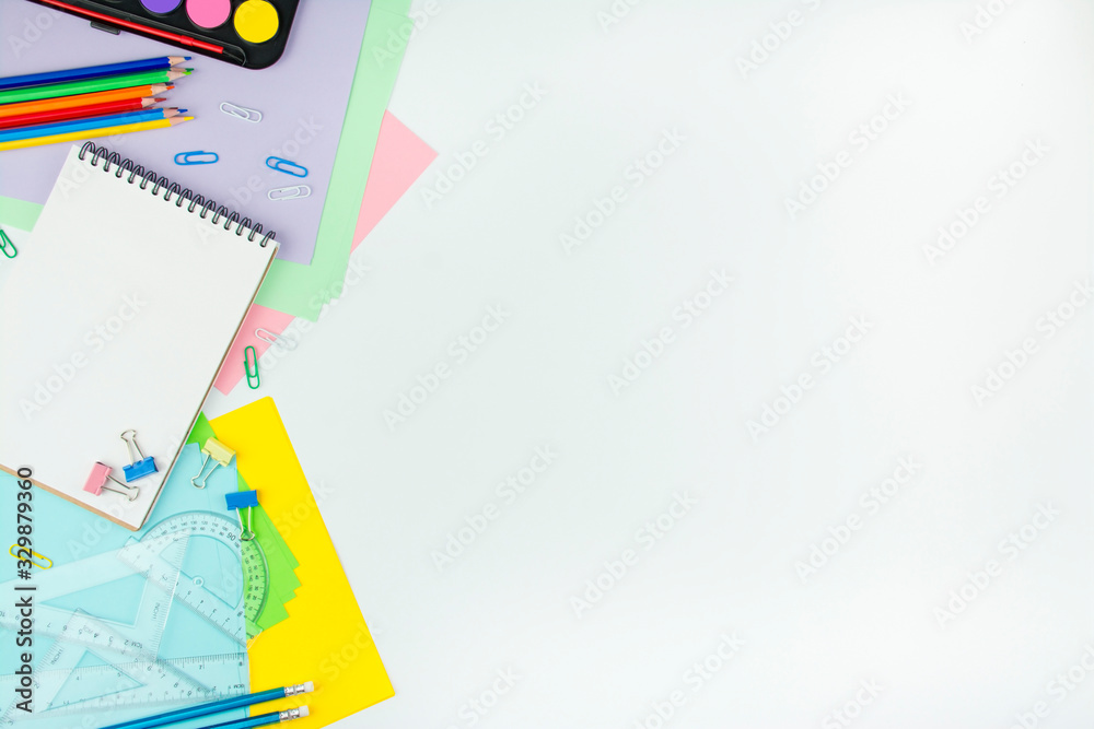 School supplies on a white background. Multicolored wooden pencils, notebook, paper clips, rulers, paper stickers. Office tools. Education concept copy space School supplies on a white background. Multicolored wooden pencils, notebook, paper clips, rulers, paper stickers. Office tools. Education concept copy space