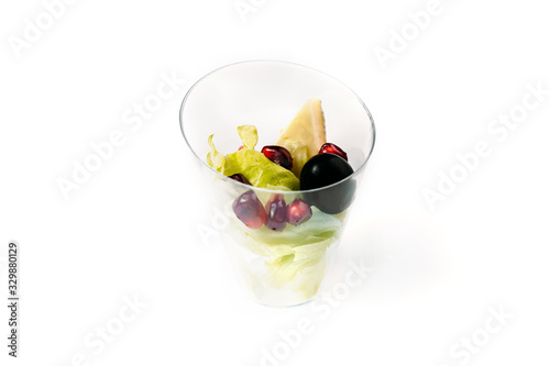 glass with salad, cheese, olive and pomegranate isolated on white background