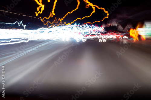 Abstract colorful dizzy car light trails taken at night on rural road from moving car