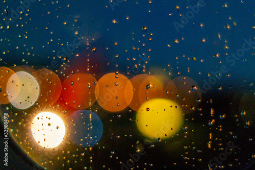 Fototapeta Naklejka Na Ścianę i Meble -  Circular round blur bokeh lights behind window with water droplets at night