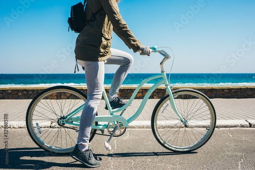 Unrecognizable young woman rides on bicycle