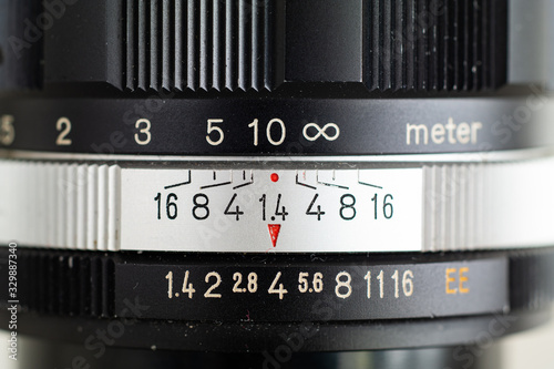 Front view macro shot of a vintage photography fast aperture prime lens with inscribed indented markings on silver aperture ring and black metal barrel photo