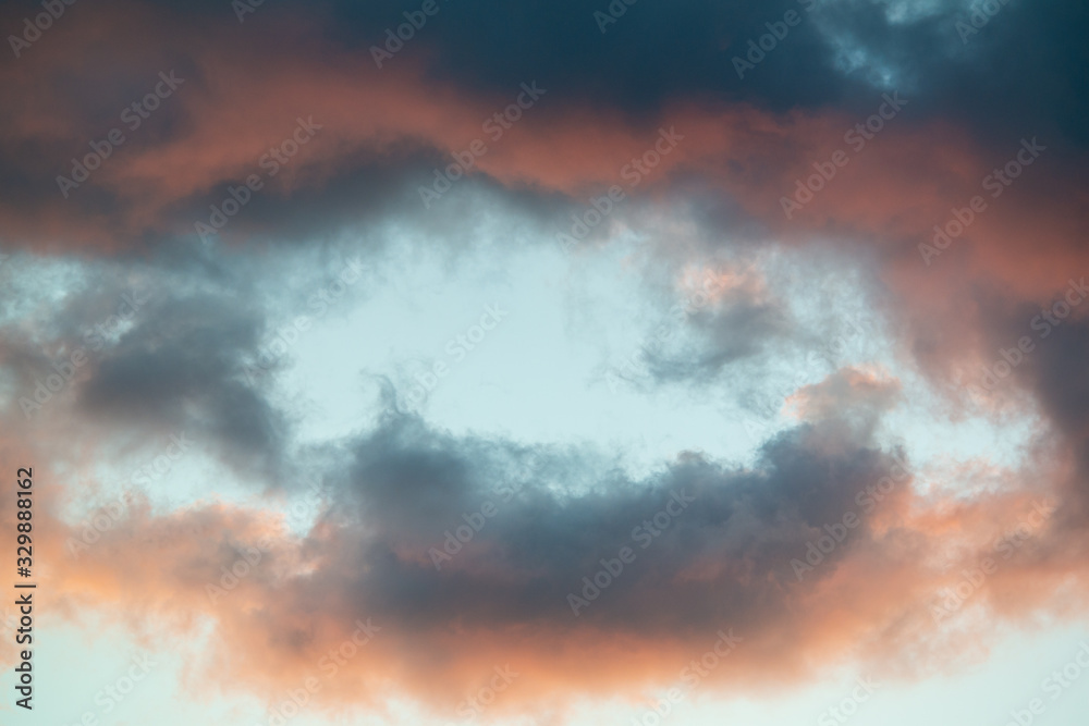 Intensely colored puffy clouds at sunset with yellows blue and pinks set against clear sky