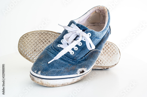 Pair or very badly worn out dirty blue casual leisure shoes with holes in them photo