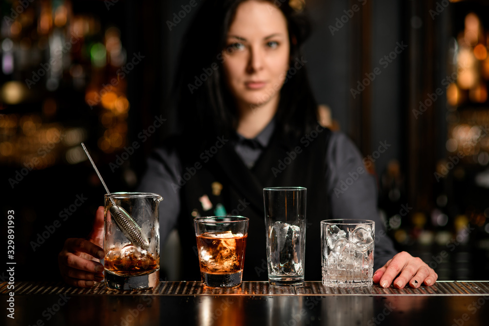 bar counter with variety of glasses with ice and alcoholic drinks.