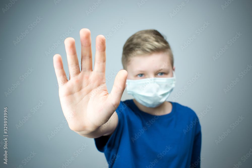 The child shows a hand with a stop. A child in an antiviral mask. The child shows a hand with a stop. A child in an antiviral mask.