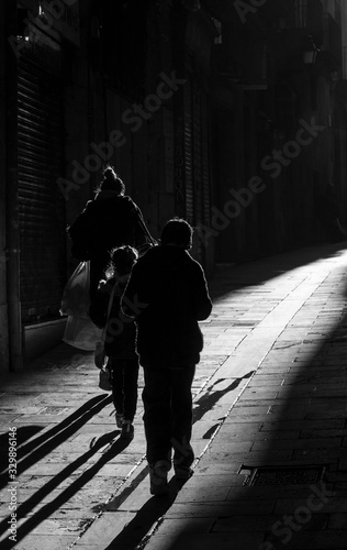 Callejuela de Barcelona con gente caminando a contraluz.