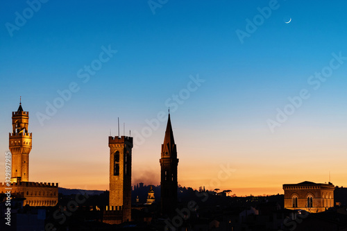 Rooftop panorama of Florence at sunset during blue hour with Palazzo Vecchio town hall, Chiesa Orsanmichele church and the Moon in the Sky