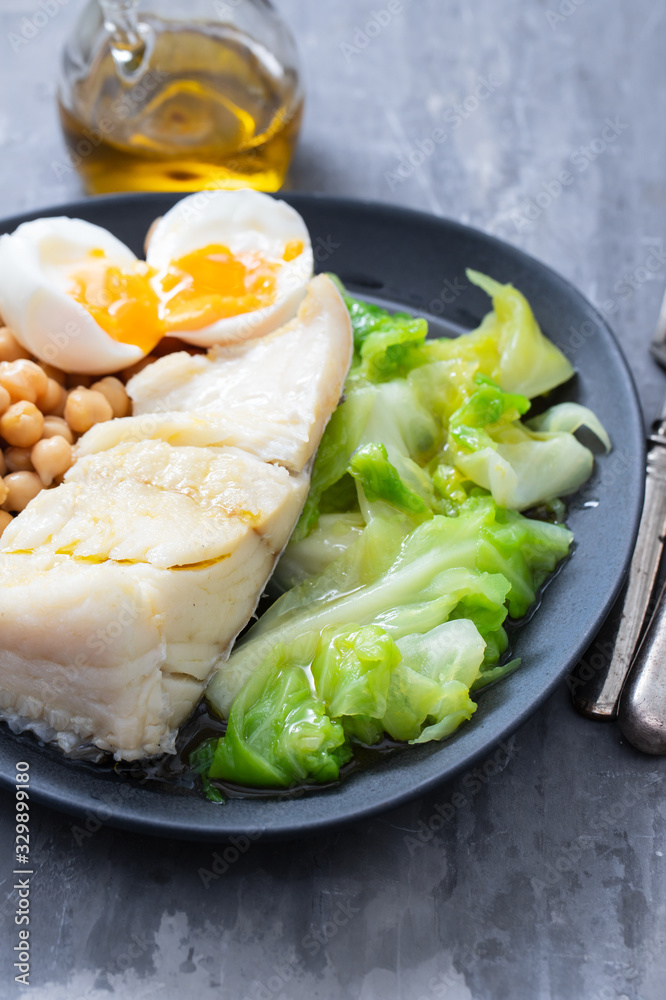 boiled cod fish with cabbage, chick pea and egg on dark dish boiled cod fish with cabbage, chick pea and egg on dark dish