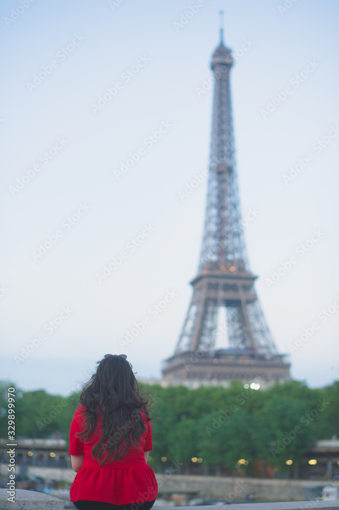 Rear View Of Woman Sitting Against Eiffel Tower