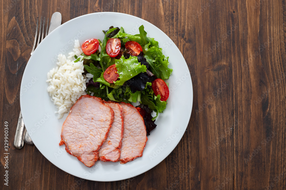 fried pork with boiled rice and salad on white plate on brown wooden background fried pork with boiled rice and salad on white plate on brown wooden background