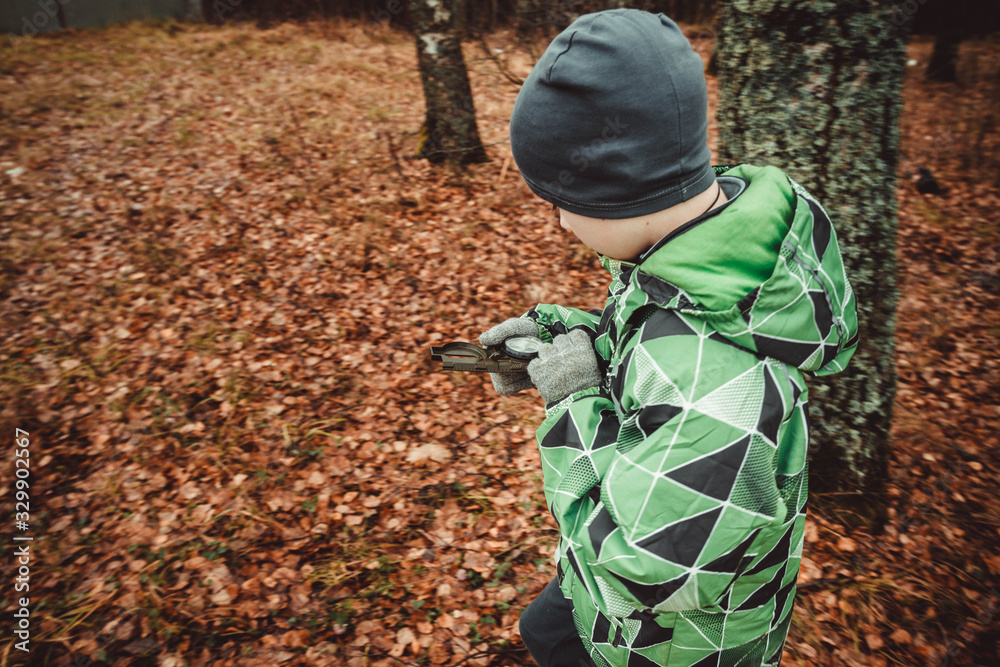 The child is guided by a compass in the woods. Autumn. A teenage boy got lost. Look for a way out of the woods. Lost alone in a strange place. The child is guided by a compass in the woods. Autumn. A teenage boy got lost. Look for a way out of the woods. Lost alone in a strange place.