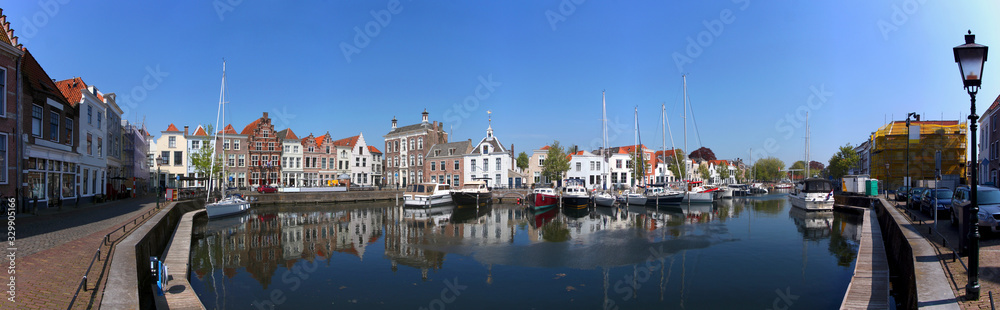 Panoramic view of the historical harbor in the old town of Goes / Netherlands with ancient house facades, motor boats and sailing yachts