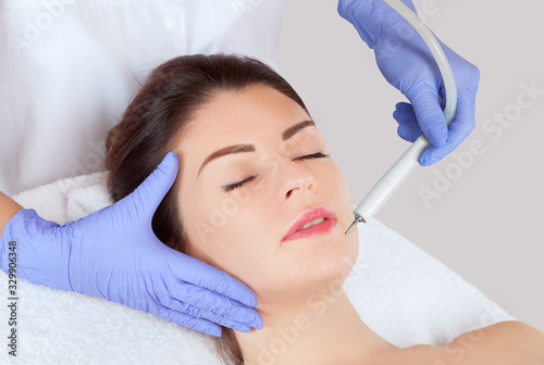 The cosmetologist makes the procedure treatment of Couperose and face cleaning of the skin of a beautiful, young woman in a beauty salon.Cosmetology and professional skin care.