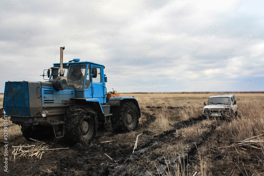 Tractor pulls a stuck car out of the fields Tractor pulls a stuck car out of the fields