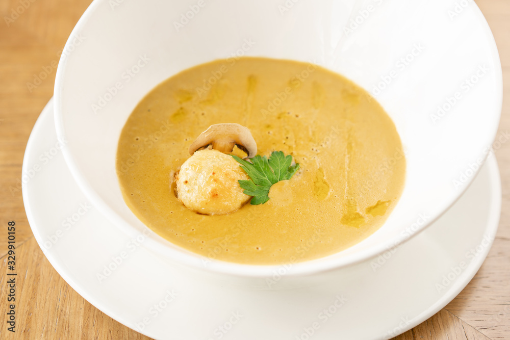 Cream-soup with porcini mushroom with croutons on wooden table. Restaurant menu