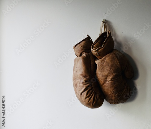 Pair of old and worn boxing gloves hang on the wall