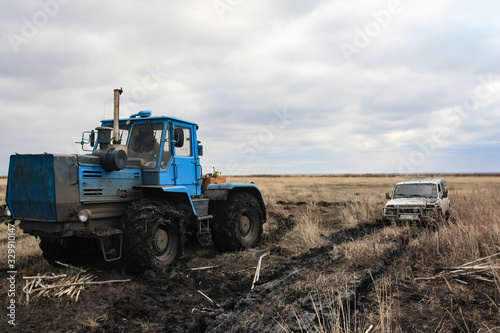 Tractor pulls a stuck car out of the fields