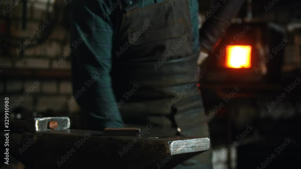 Forging industry - a man putting his instruments on the anvil Forging industry - a man putting his instruments on the anvil