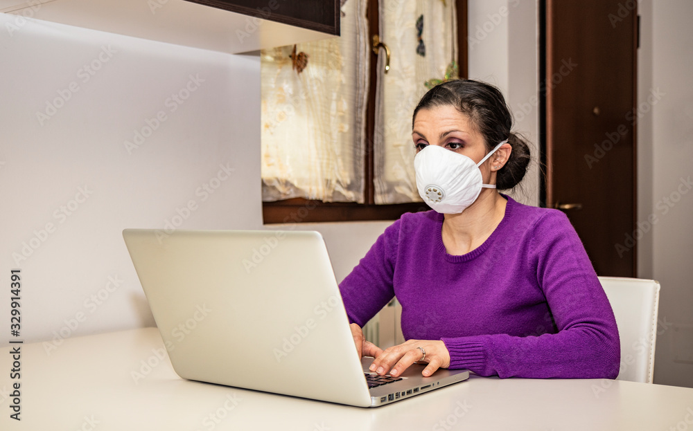 Coronavirus, Covid-19. Stay at home. Quarantine. Protection mask. A beautiful Caucasian woman forced to stay home to prevent virus infection, works on the laptop. Smart Working.
